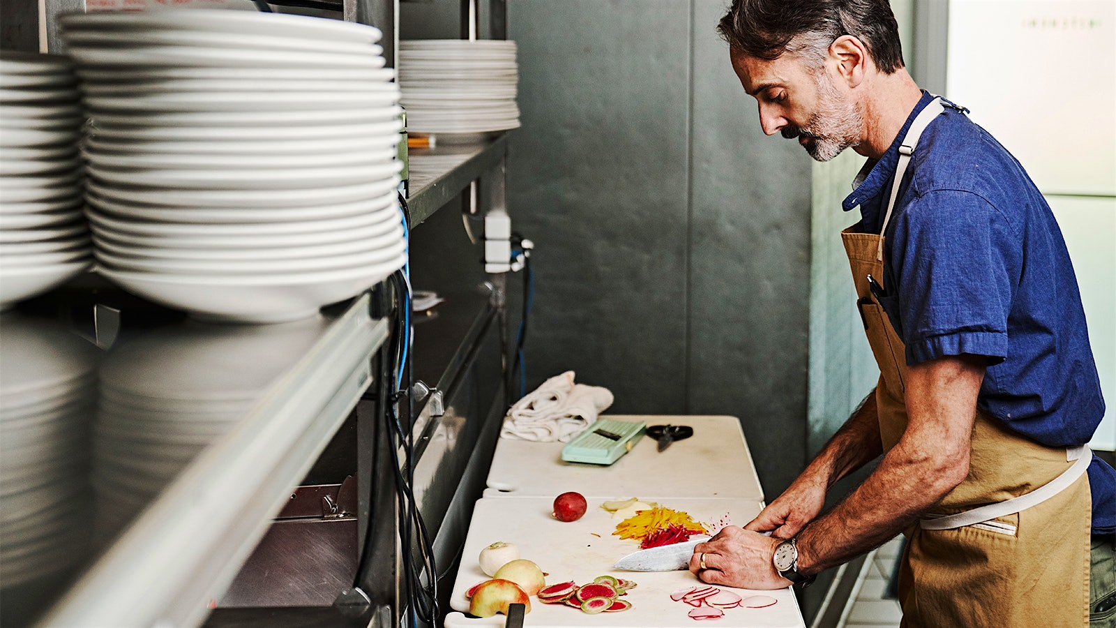 Portrait of Miller Union chef and author Steven Satterfield chopping vegetables in his restaurant kitchen
